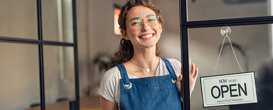 Small business owner welcoming customers with an open sign on the door