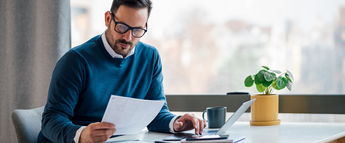 Image of a Person Reviewing Financial Documents on a Laptop