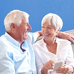 Older couple smiling and holding cell phone